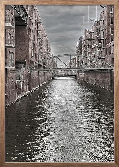 Poster mit Kanal in der Speicherstadt Hamburg in einer monochromen Interpretation mit einem Rahmen in Eiche Poster mit Kanal in der Speicherstadt Hamburg in einer monochromen Interpretation mit einem Rahmen in Eiche