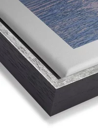 Wandbild mit Sonnenuntergang am Meer in warmer Farbstimmung auf Leinwand mit einem schwarz-silbernen Rahmen