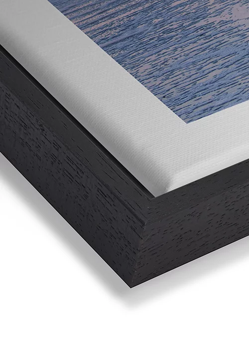 Wandbild mit Sonnenuntergang am Meer in warmer Farbstimmung auf Leinwand mit einem schwarzen Rahmen