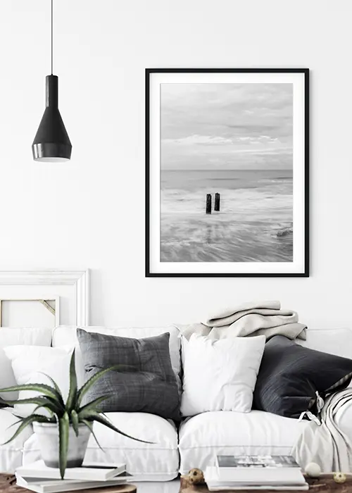 Poster mit zwei Pfählen als Überreste eines Wellenbrechers im stürmischen Meer an einer Wand über einem Sofa
