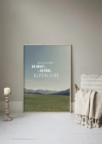 Poster mit Blick über eine Wiese auf die Berge im Hintergrund und Motivationsspruch an eine Wand gelehnt