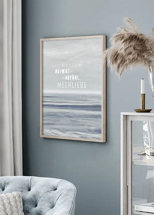 Poster mit Meer, Himmel und Motivationsspruch an einer Wohnzimmerwand