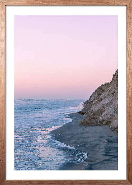 Poster mit Sonnenuntergang am Meer in warmer Farbstimmung mit einem Rahmen in Eiche