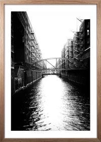Poster der Hamburger Speicherstadt mit Kanal in schwarz-weiß mit einem Rahmen aus Eiche
