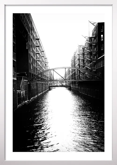 Poster der Hamburger Speicherstadt mit Kanal in schwarz-weiß mit einem weißen Rahmen Poster der Hamburger Speicherstadt mit Kanal in schwarz-weiß mit einem weißen Rahmen