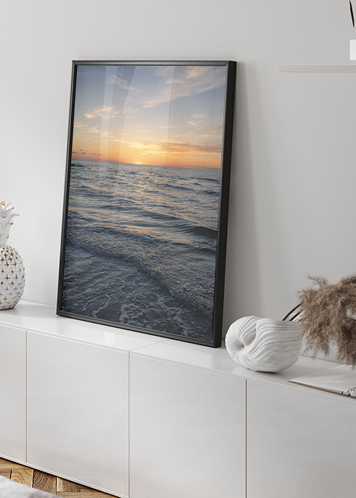 Poster mit Meer und Abendrot auf einem Sideboard stehend