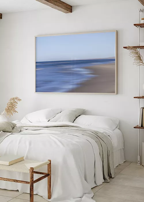 Poster mit abstrakter Darstellung von Meer und Strand über einem Bett hängend