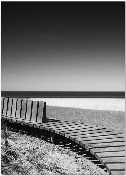 Poster mit einer geschwungenen Holzbank am Strand in schwarz-weiß