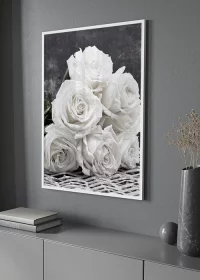 Poster mit einem Strauß weißer Rosen über einem Sideboard hängend