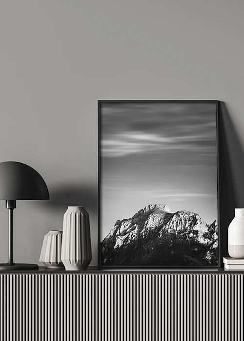 Poster mit einem Berggipfel in Schwarz-Weiß auf einer Kommode