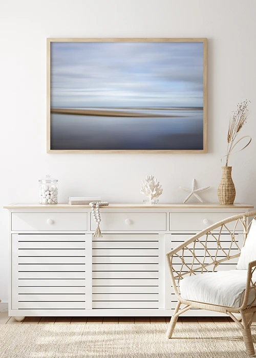 Poster mit abstrakter Darstellung von Himmel und Meer über einer weißen Kommode hängend