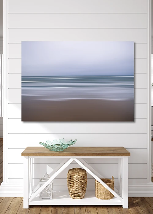 Poster mit Strand, Meer und Himmel in abstrakter Darstelllung an einer Holzwand hängend