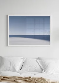 Poster mit abstrakter Darstellung von Strand, Meer und Himmel über einem Bett hängend