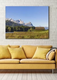 Poster mit Alpenlandschaft in einer herbstlichen Stimmung über einem Sofa hängend