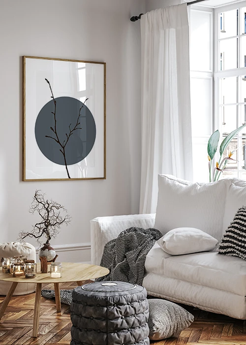 Poster in minimalistischem Japandi-Style mit einem schwarzen Zweig vor einem grauen Kreis an einer Wohnzimmerwand hängend