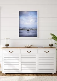 Poster mit einer kleinen Seemöwe am Strand von Dänemark über einem weißen Sideboard hängend