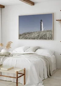 Poster mit einem weißen Leuchtturm in den Dünen Dänemarks über einem Bett hängend