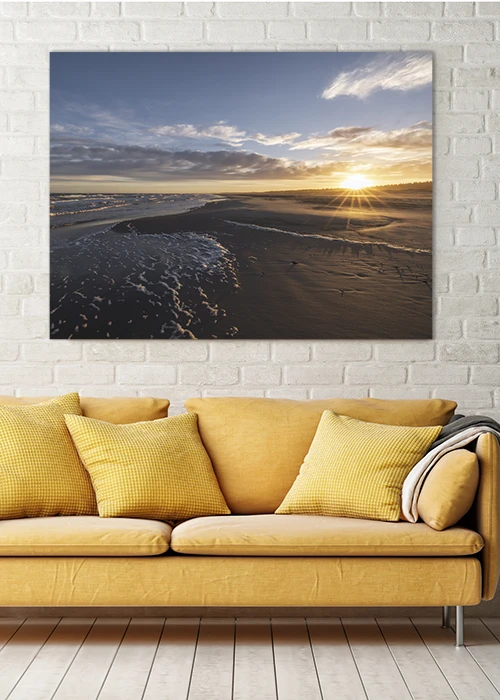 Wandbild AluDibond mit Sonnenaufgang am Strand, aufgehängt über einem Sofa