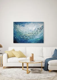 Premiumposter – Grafikmotiv mit einem Fischschwarm im opelblauen Meer, aufgehängt über einem Sofa.