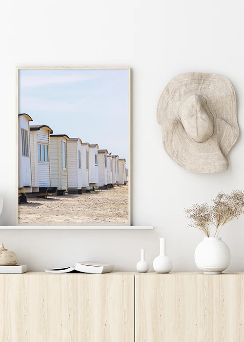 Inspiration – Poster mit Badehäusern am Strand, aufgehängt über einem Sideboard.